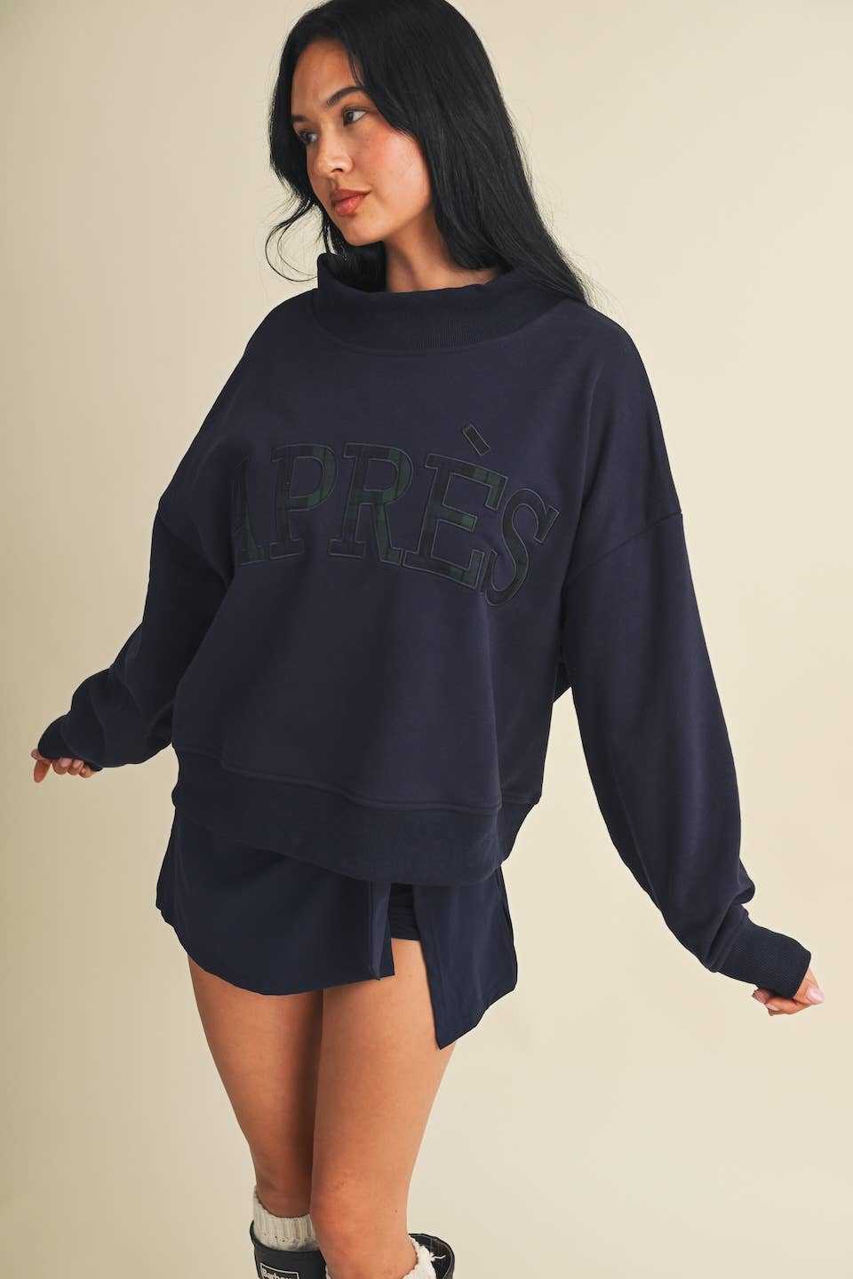 Model wearing an oversized mock neck sweatshirt with embroidered Après lettering and matching shorts