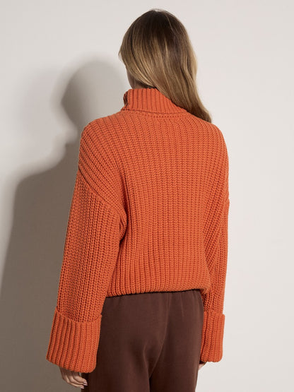 Chunky ribbed orange turtleneck jumper with wide cuffed sleeves, back view