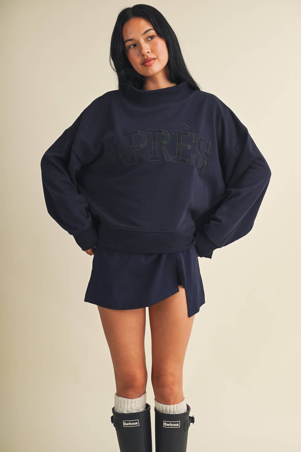 Model wearing oversized navy mock neck sweatshirt with embroidered Après lettering paired with matching shorts