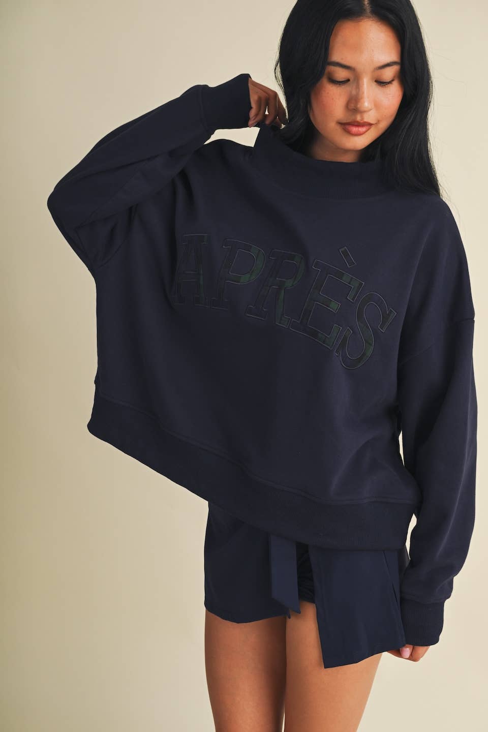 Model wearing oversized navy mock neck sweatshirt with embroidered Après lettering and matching shorts