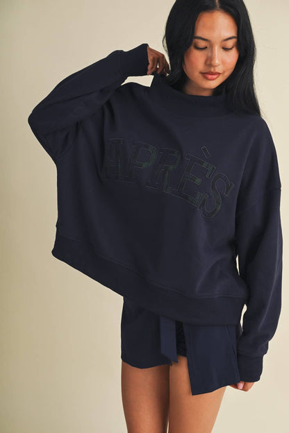 Model wearing oversized navy mock neck sweatshirt with embroidered Après lettering and matching shorts