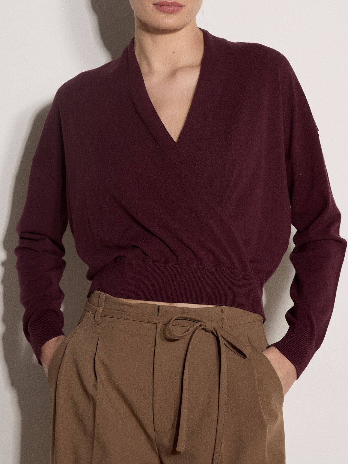 Woman wearing a cropped wrap-style fine knit jumper with long sleeves and ribbed hem
