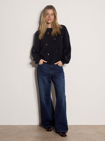 Model wearing a navy knit jumper with delicate floral embroidery and wide-leg jeans