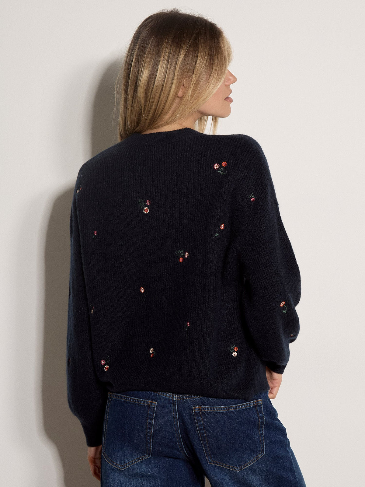 Back view of a navy knit jumper with scattered small embroidered floral details throughout