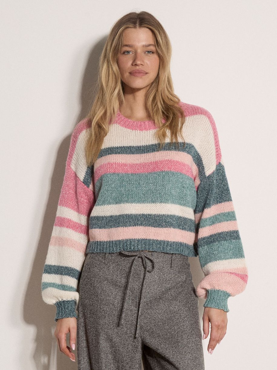 Model wearing a cropped striped knit jumper with balloon sleeves and ribbed cuffs