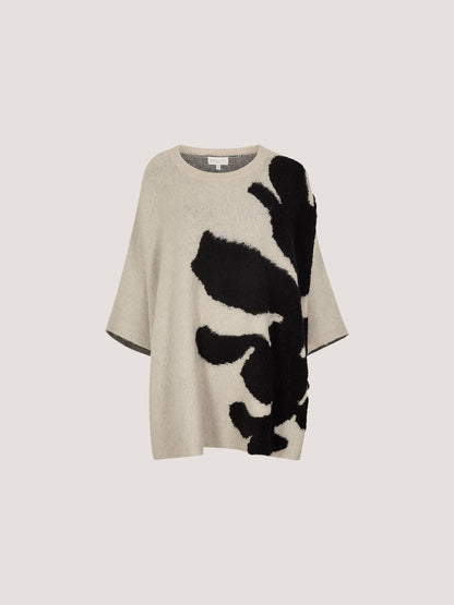 Oversized knit cape jumper with bold abstract black floral intarsia pattern on neutral ground