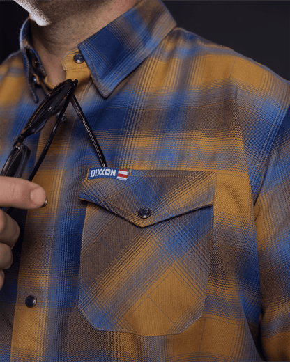 Close-up detail of Dixxon flannel chest pocket with snap button and brand label patch