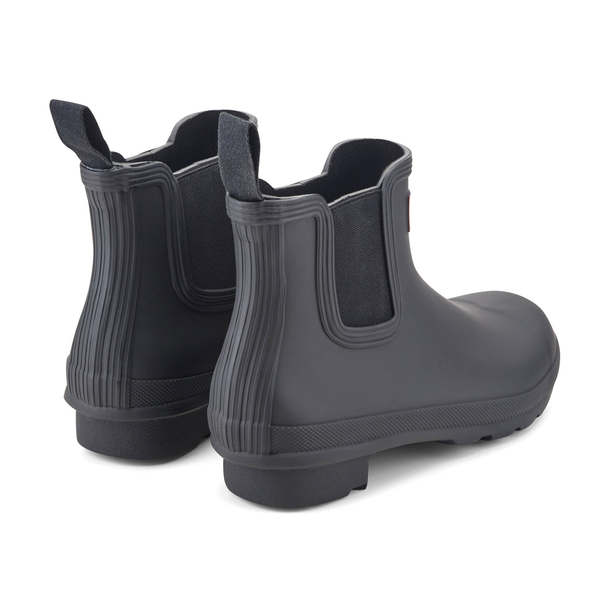 Pair of black rubber Chelsea ankle booties shown from rear angle, elastic side panels visible