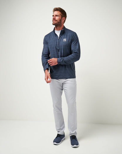 Man wearing Travis Mathew navy heather quarter-zip pullover with NY Yankees logo, styled with gray pants